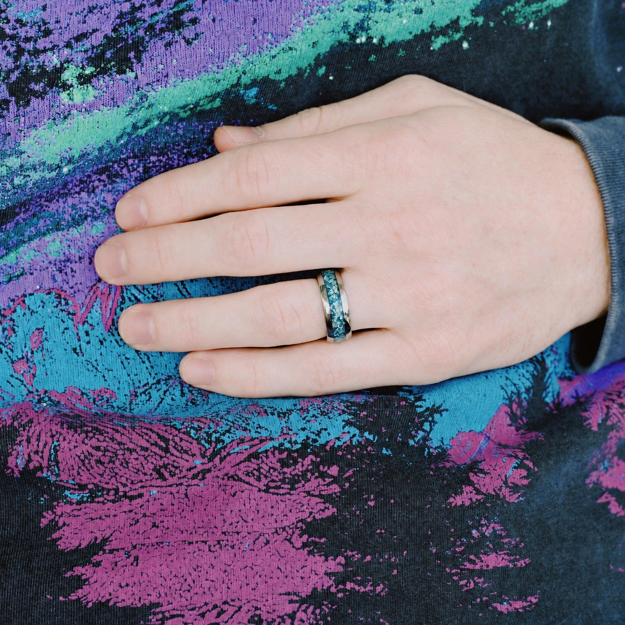 Silver-tone tungsten ring with blue crushed-stone inlay worn on a hand, wider view